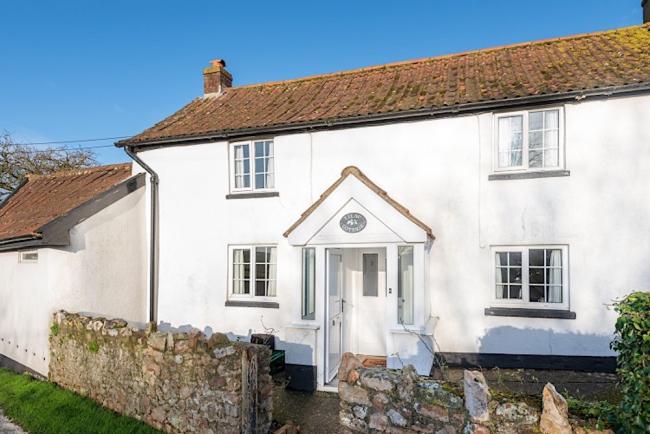 A double-fronted holiday cottage exterior with a small walled front garden