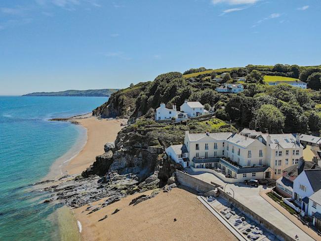 aerial view or a beach with a small seaside village overlooking the sands