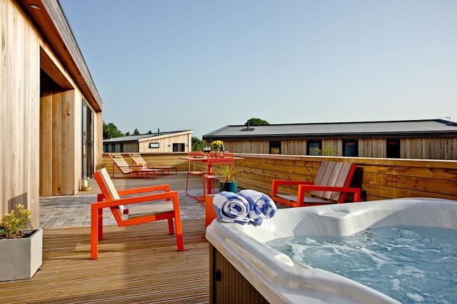 holiday lodge deck with a hot-tub, table and chairs