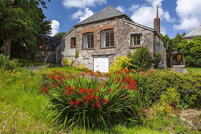 Exterior or a stone-built barn conversion surrounded by a flower-filled garden