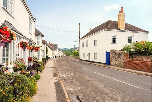 Cottages with hanging flower basket line a quiet village street.