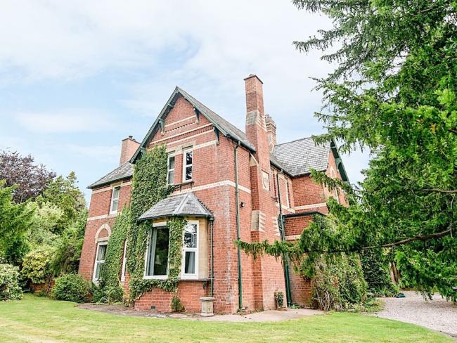 Brick-built Victorian vicarage surrounded by a tree-lined garden.