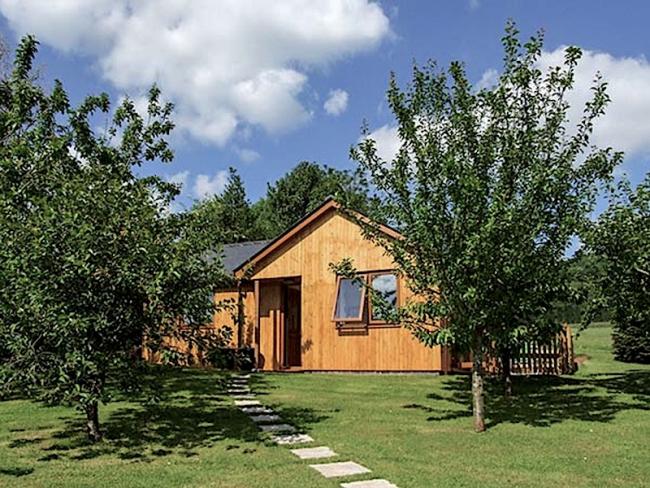 Gable end of a wooden eco-lodge in an orchard setting.