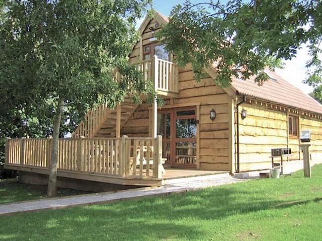 Exterior of a wooden eco-lodge with stairs to the 1st floor and a wide deck.