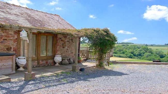 Cloistered extrior of a single-storey barn conversion with a creeper-covered pergola.