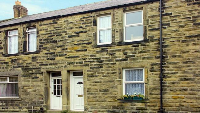 Stone-built terraced cottage with a flower-filled window basket.