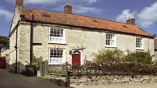 A semi-detached cottage overlooks a stone-walled front garden.