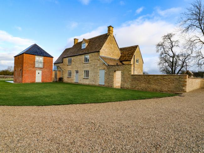 Exterior of a large stone-built, 3-storey Oxfordshire farmhouse and garden.