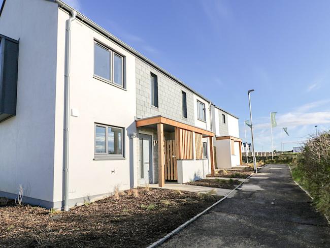 A terrace of contemporary Cornish seaside cottages bathed in sunshine.