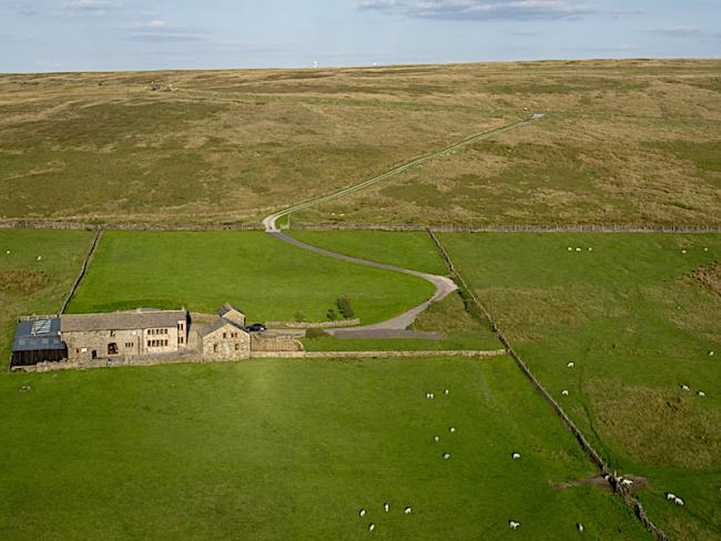 An isolated Pennine farm house is surrounded by empty moorland.