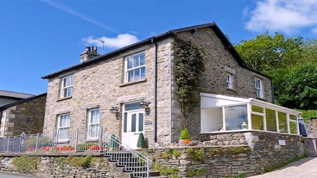 A large Cumbrian with spacious sunroom with a raised, flower-filled terrace.
