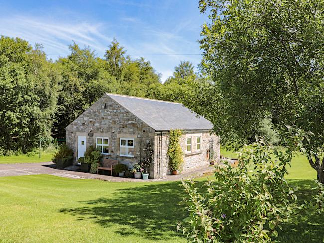 A single storey Northumberland barn conversion surrounded by a large, tree-fringed lawn