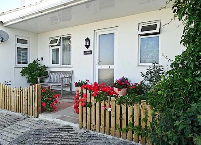 Exterior of a single-storey coach house convrsion with a small, flower-filed front garden.