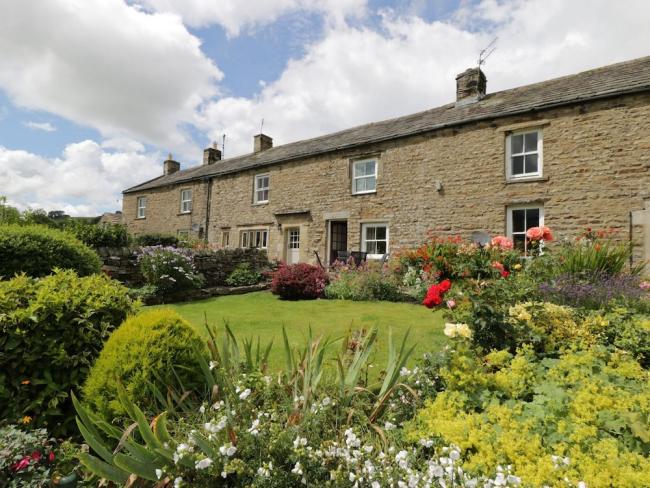 A stone-built terrace of cottages with flower-filled gardens in Swaledale.