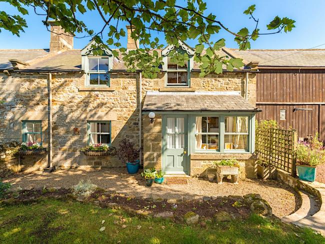 Exterior and front garden of a 2-storey stone-built Northumberland holidy cottage.