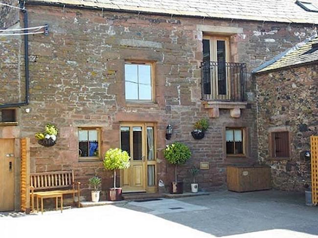 A stone Penrith holiday home with a 1st floor Juliet Balcony overlook a paved courtyard.