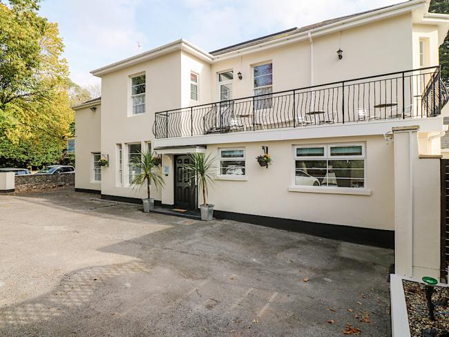 Exterior of a large Victorian house in Torquay with a long balcony overlooks a courtyard.