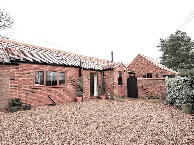Exterior of a brick-built holiday bungalow in Fakenham with spacious off-road parking.