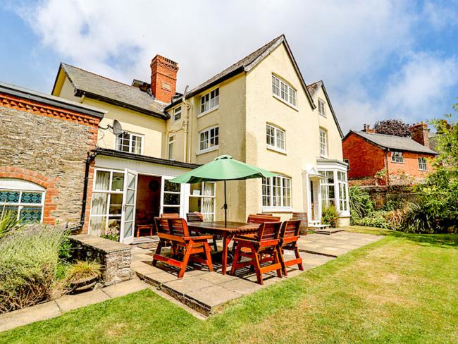 3 storey exterior of a large modern Shropshire holiday home with outdoor dining facilities and a large laen.