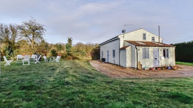 A chalet bungalow for self-catering holidays in Norfolk is surrounded by open fields.