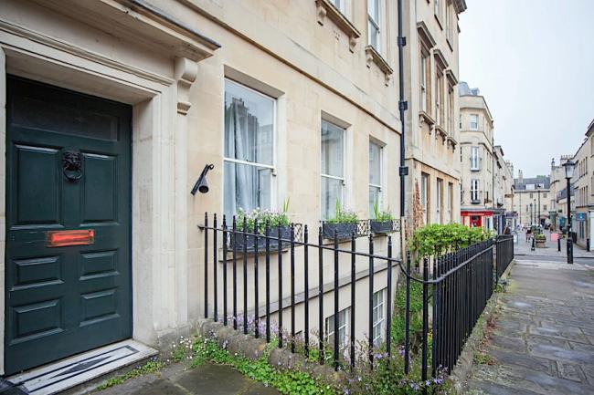 A 4-storey, classic Bath-stone terraced house overlooking a street.