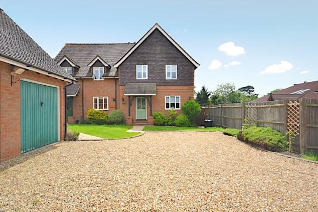 A modern New Forest holiday home overlooks a large shingle drive and a garage.