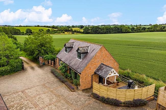 A Northamptonshire barn conversion with a paved courtyard surrounded by open fields.