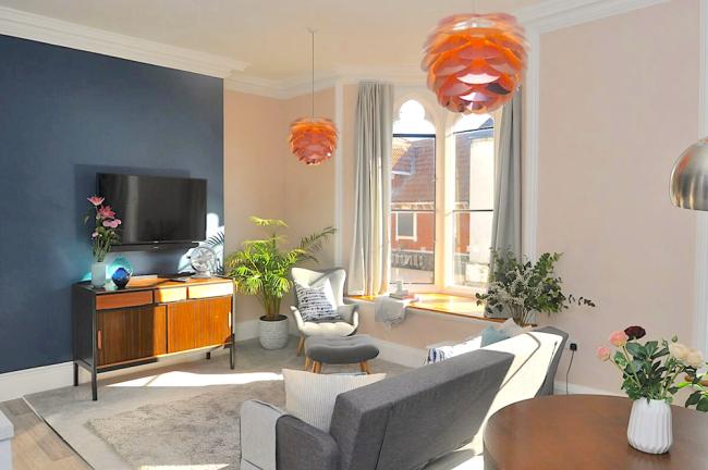 Stylish, sunlit lounge interior with sofa, armchairs and wide-screen TV