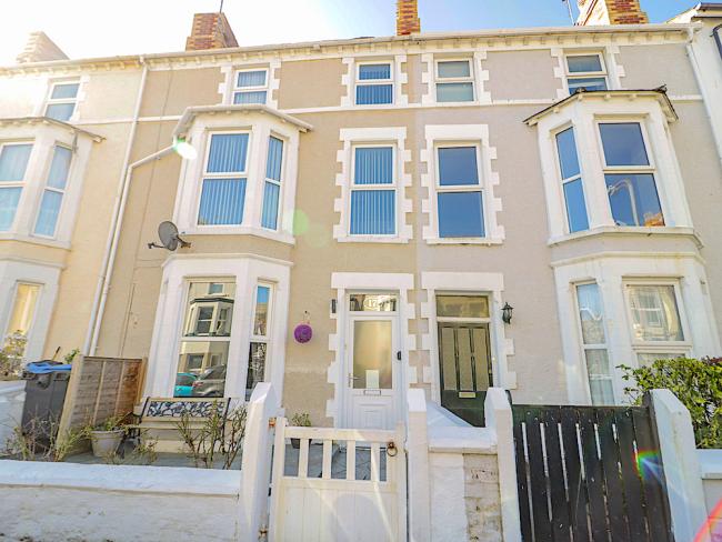 Exterior of a 3-storey Victorian townhouse in Llandudno with large bay windows.