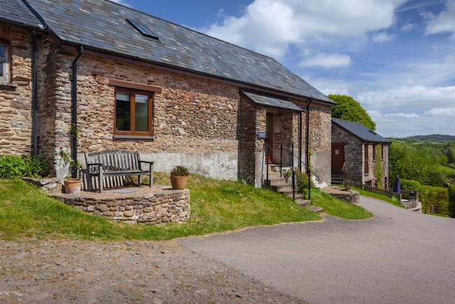 An Exmoor stone barn conversion overlooks a bend in a country lane. 