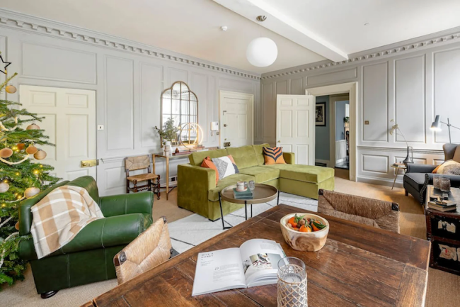 A spacious, wood-panelled lounge with leather sofas, hardwood coffee table and flooring.