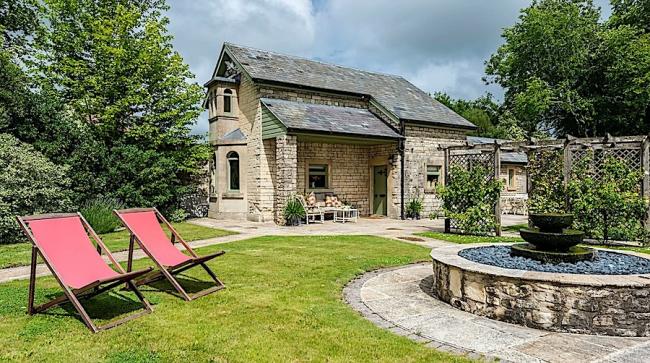 A gsrden path lesds past an ornamental fountain to sa stone. built Somerset holiday cottage