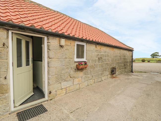 Stone-built bungalow exterior overlooking a paved courtyard in Robin Hoods bay