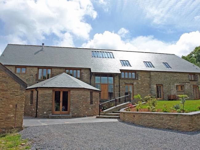 Exterior of a large 2-storey barn conversion surrounded by lawns.