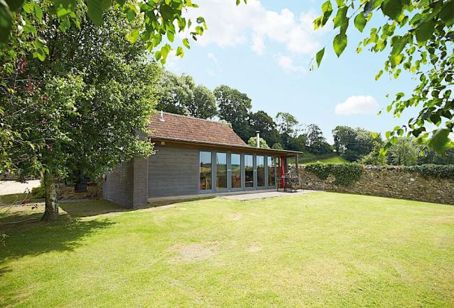 A contemporary wooden holiday lodge in Est Devon overlooking a large walled lawn.