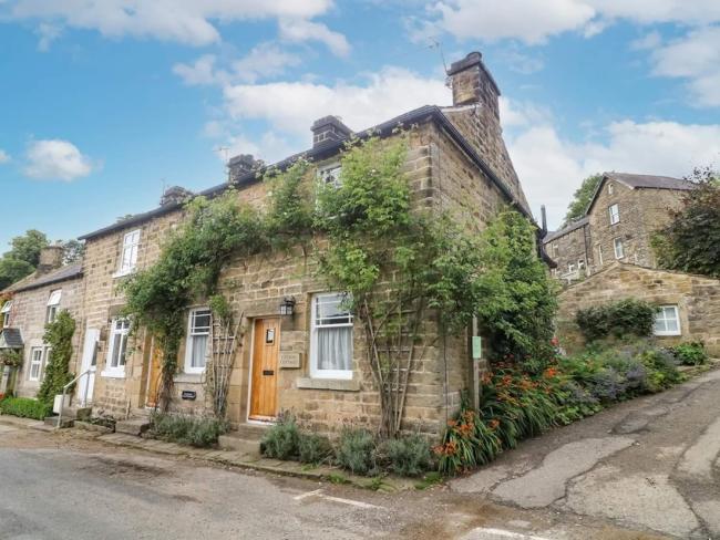 A vine-clad, stone-built, corner cottage on an empty village street.