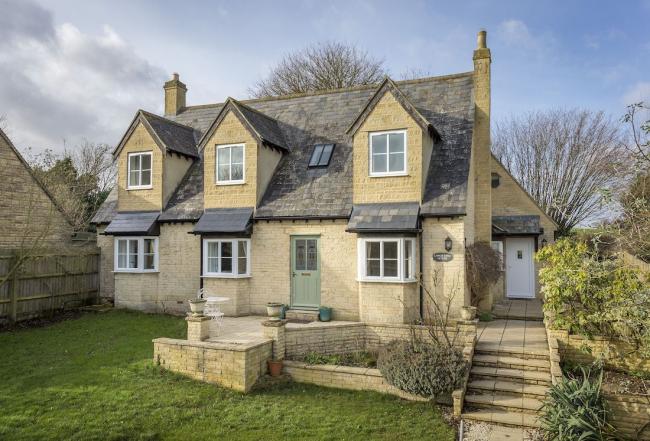 Exterior or a modern Cotswold honeystone house with triple bay windows