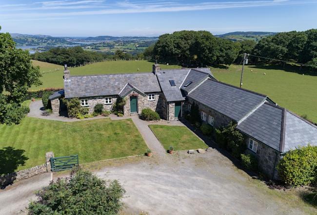 L-shaped exterior of a barn conversion surrounded by open fields.