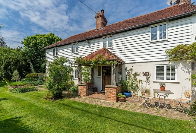 Exterior of a weather-boarded East Sussex Cottage and lawned garden.