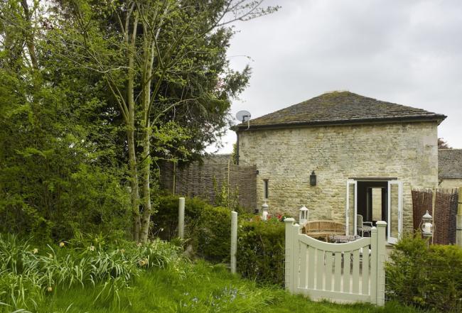 A stone-built barn conversion with a garden protected by a low hedge.