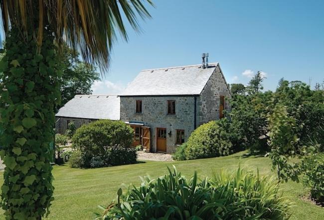 Stone-built Cornish barn conversion surrounded by shrub-lined, lawns.
