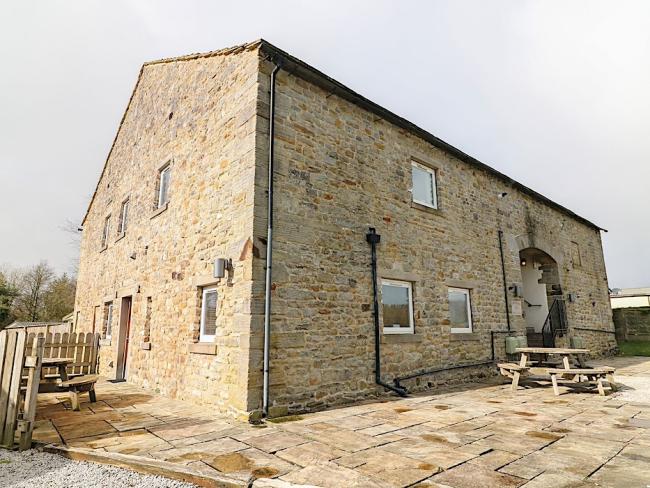 A tall, sdtone-built barn conversion with a spacious courtyard.
