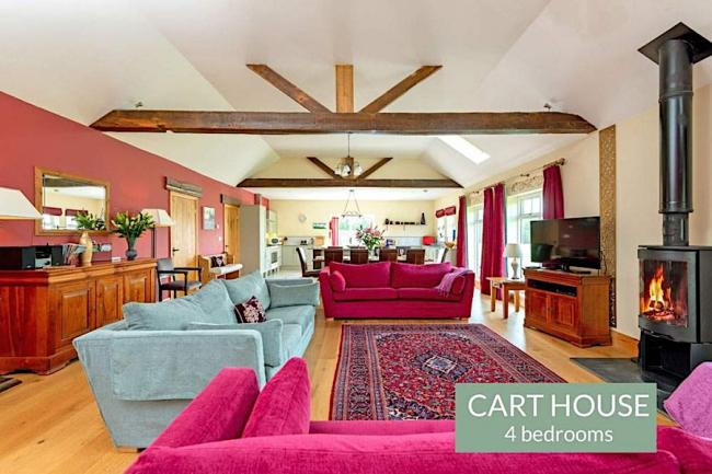 A large open plan lounge with beamed ceiling, widescreen TV and comfy sofas.
