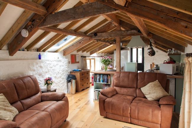 A cottage lounge with a pine-beamed ceiling and comfortable leather sofas.