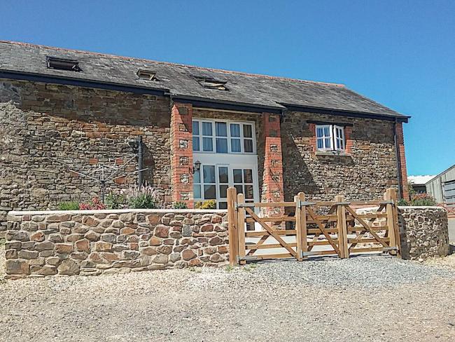 A stone-built North Devon barn conversion overlooks a paved courtyard.