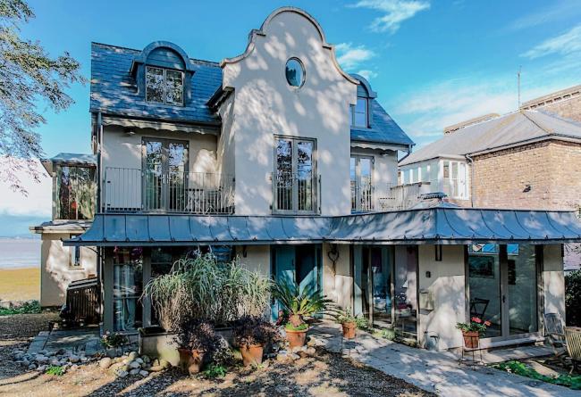 A 4-storey house with balconies and floor-to-ceiling windows within a well-kept, mature garden.