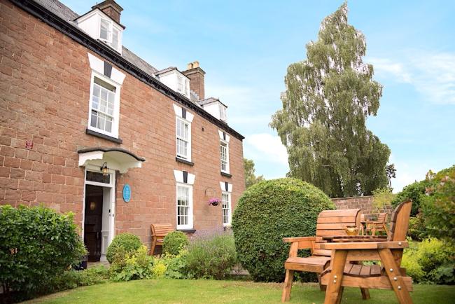 Exterior of a large, 3-storey, brick-built Wye Valley cottage with a large lawn.