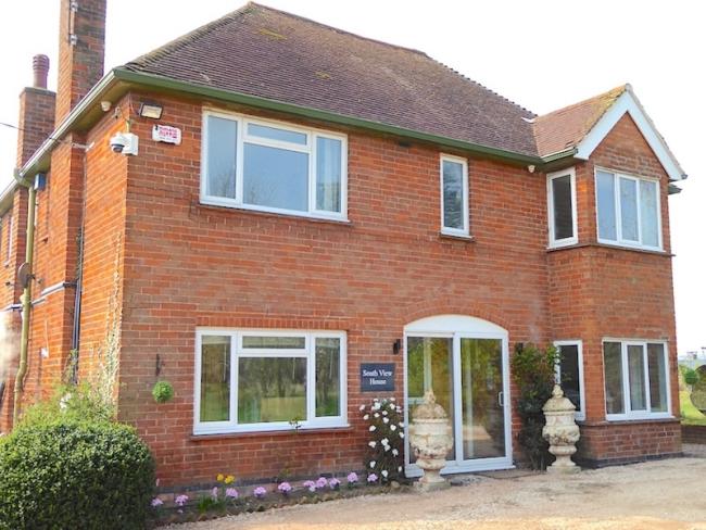 Double-fronted exterior of a rural holiday cottage with a large paved terrace.