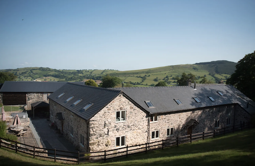 Exterior view of a stonebuilt, L-shaped barn conversion in the Shropshire Countryside.