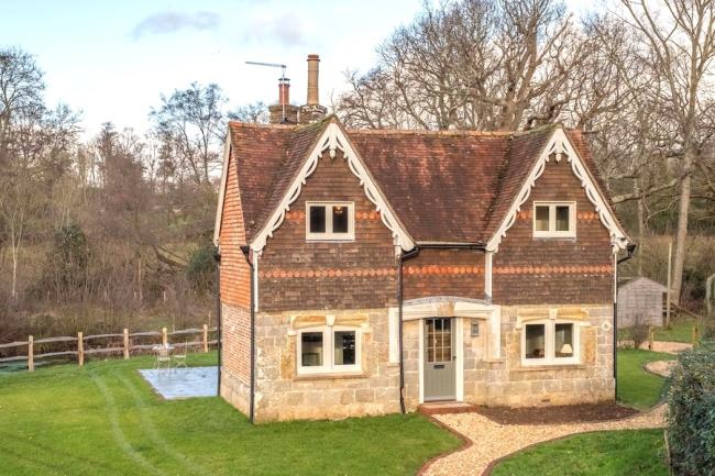 Twin-gabled extertior of a Kent farmhouse surrounded by a large, fenced lawn